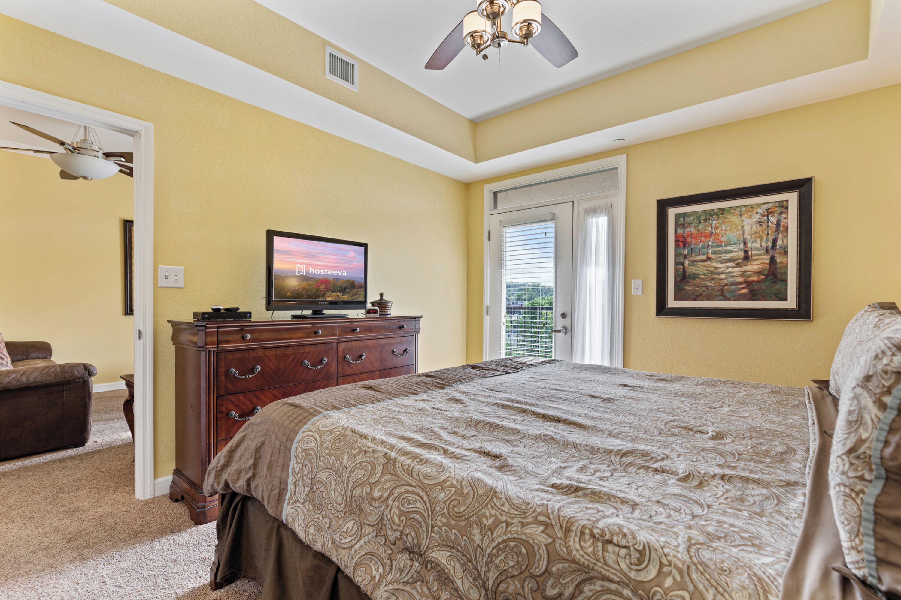 Une chambre à coucher avec un lit, une commode, un téléviseur et un tableau accroché au mur.