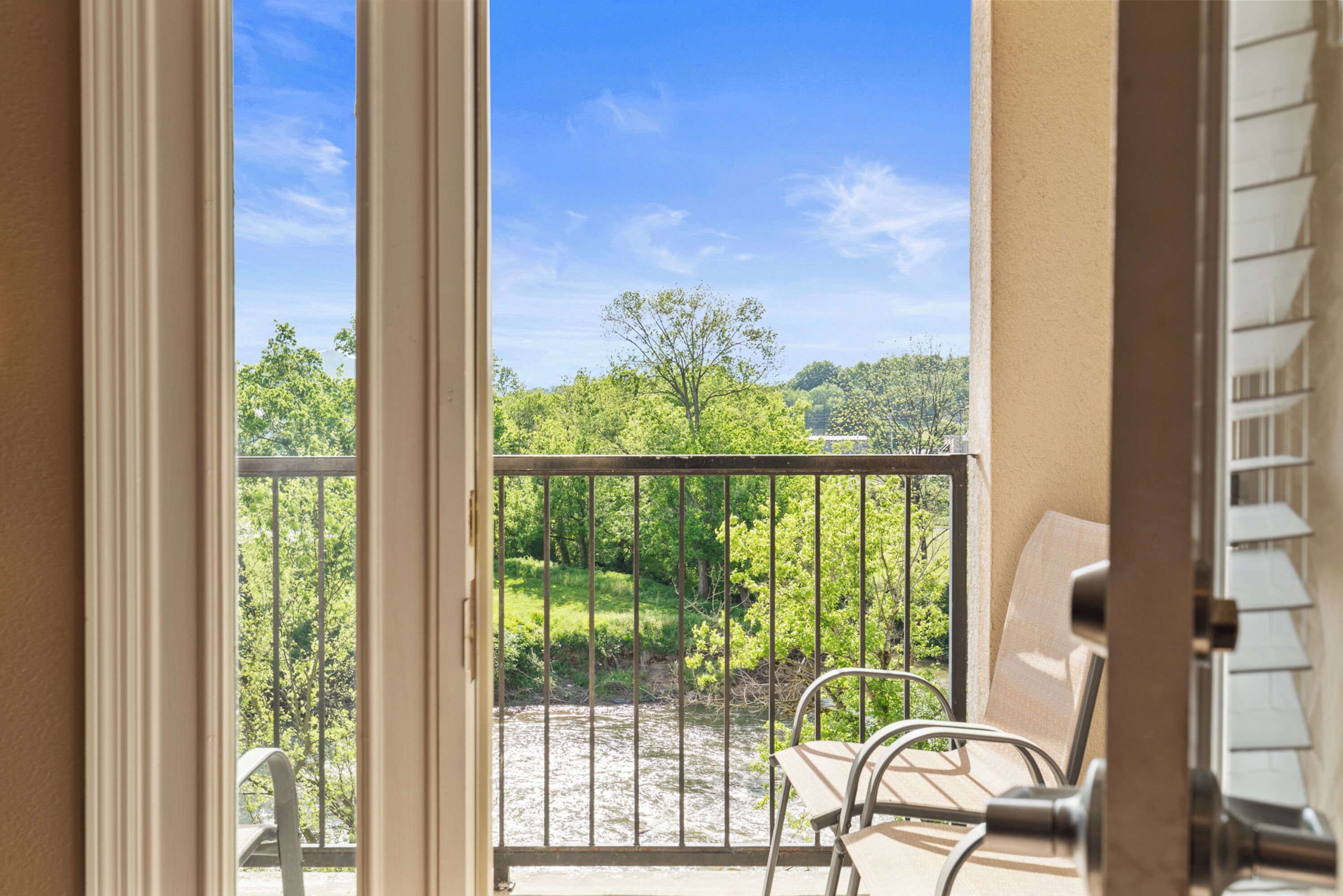 A balcony with a view of a river and greenery.