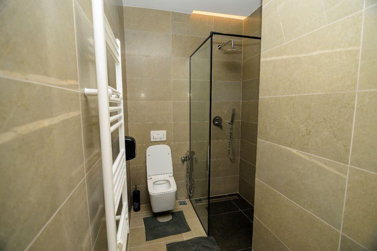 Un baño moderno con ducha de vidrio, inodoro blanco y perchero para toallas.