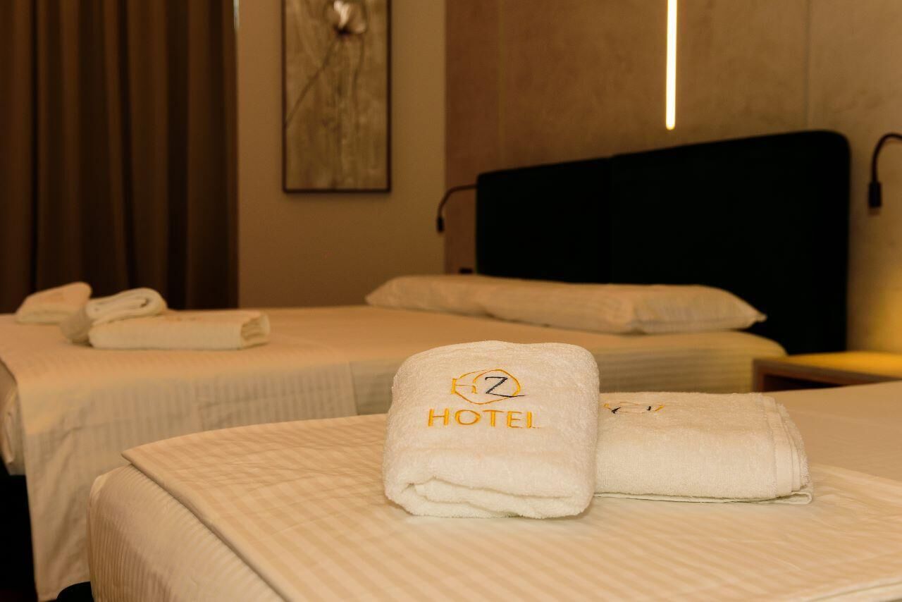 Une chambre d’hôtel avec deux lits, chacun agrémenté d’une serviette blanche soigneusement pliée et d’un oreiller.
