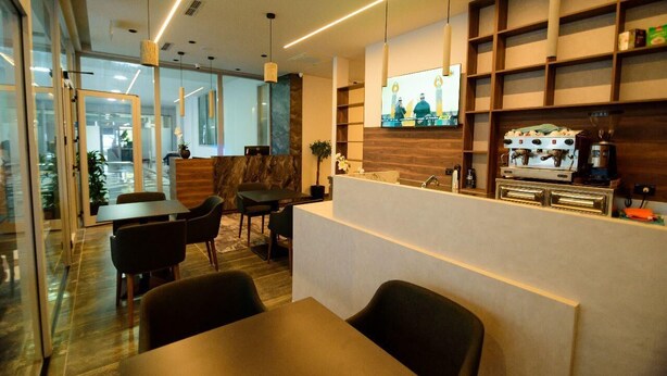 A modern interior with a reception desk, seating area, and a coffee machine. - Hotel Zeneli Vlore (Vlorë)