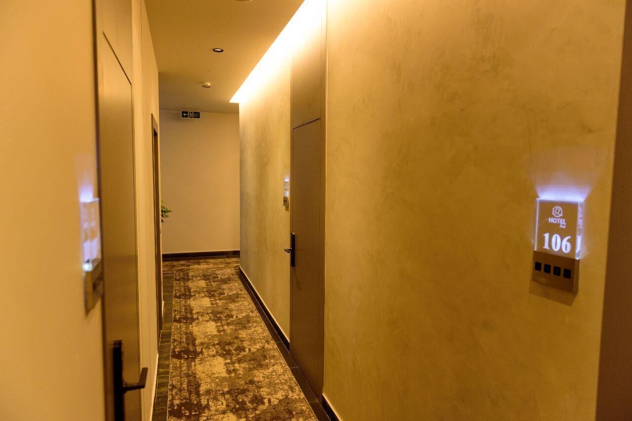 A hotel hallway with a textured carpet, a wall-mounted sign indicating room number 106, and a door with a handle.