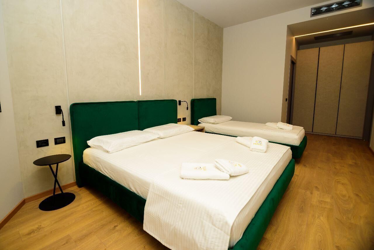A hotel room with two beds, a small round table, and a wardrobe.