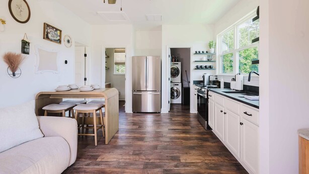 A modern kitchen with a central island, stainless steel appliances, and a dining area with a sofa and chairs. - Walk2OldTown!  Modern Lux Private Carriage House (Bluffton)