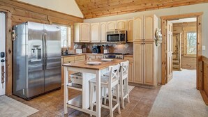 Une cuisine dotée de meubles en bois, d’appareils électroménagers en acier inoxydable et d’une table à manger en bois, assortie de chaises.
