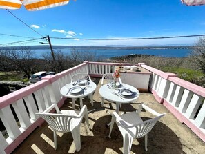 An outdoor patio with white chairs and tables, a pink railing, and a view of a lake. - Holiday house Luky (Dramalj)