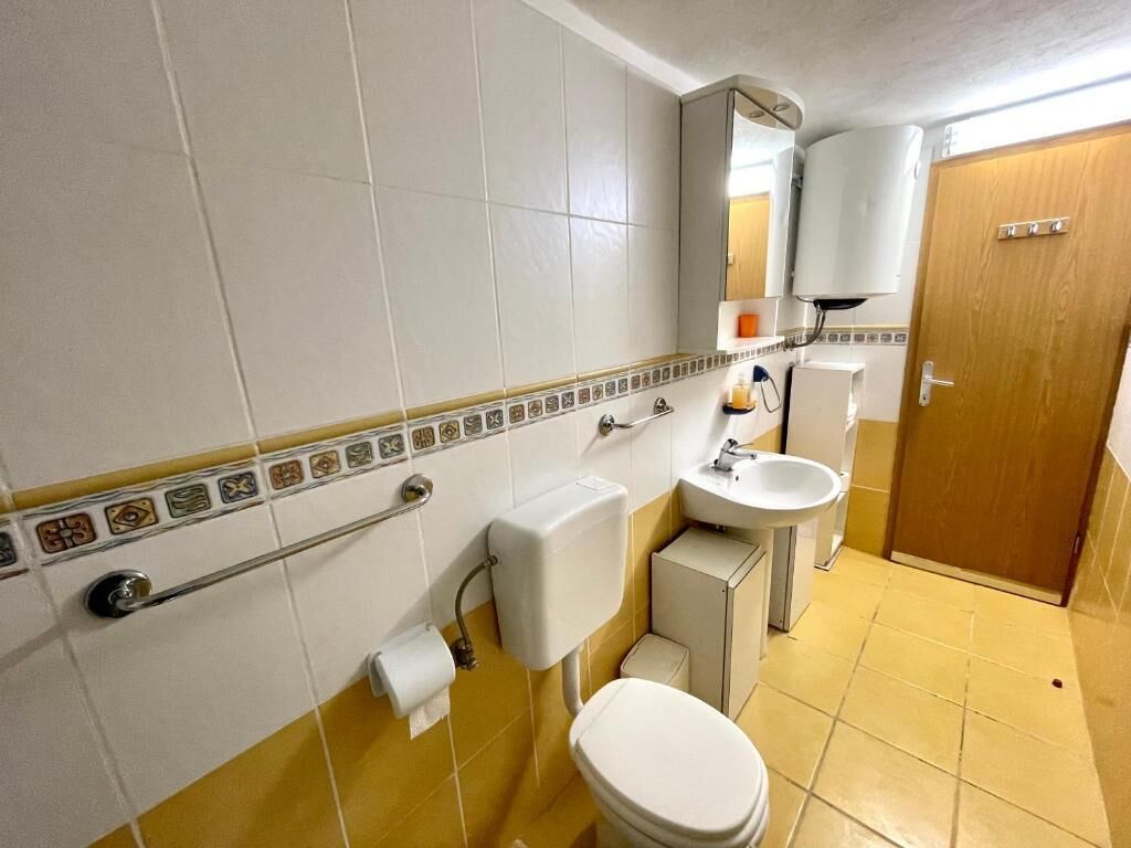 A bathroom with a toilet, sink, and mirror.
