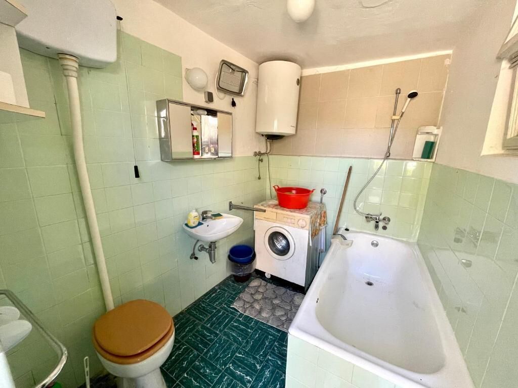 Une petite salle de bain comprenant des toilettes, un lavabo, un lave-linge et une baignoire.