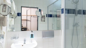Un baño moderno con lavamanos blanco, inodoro y ducha con mampara de vidrio.