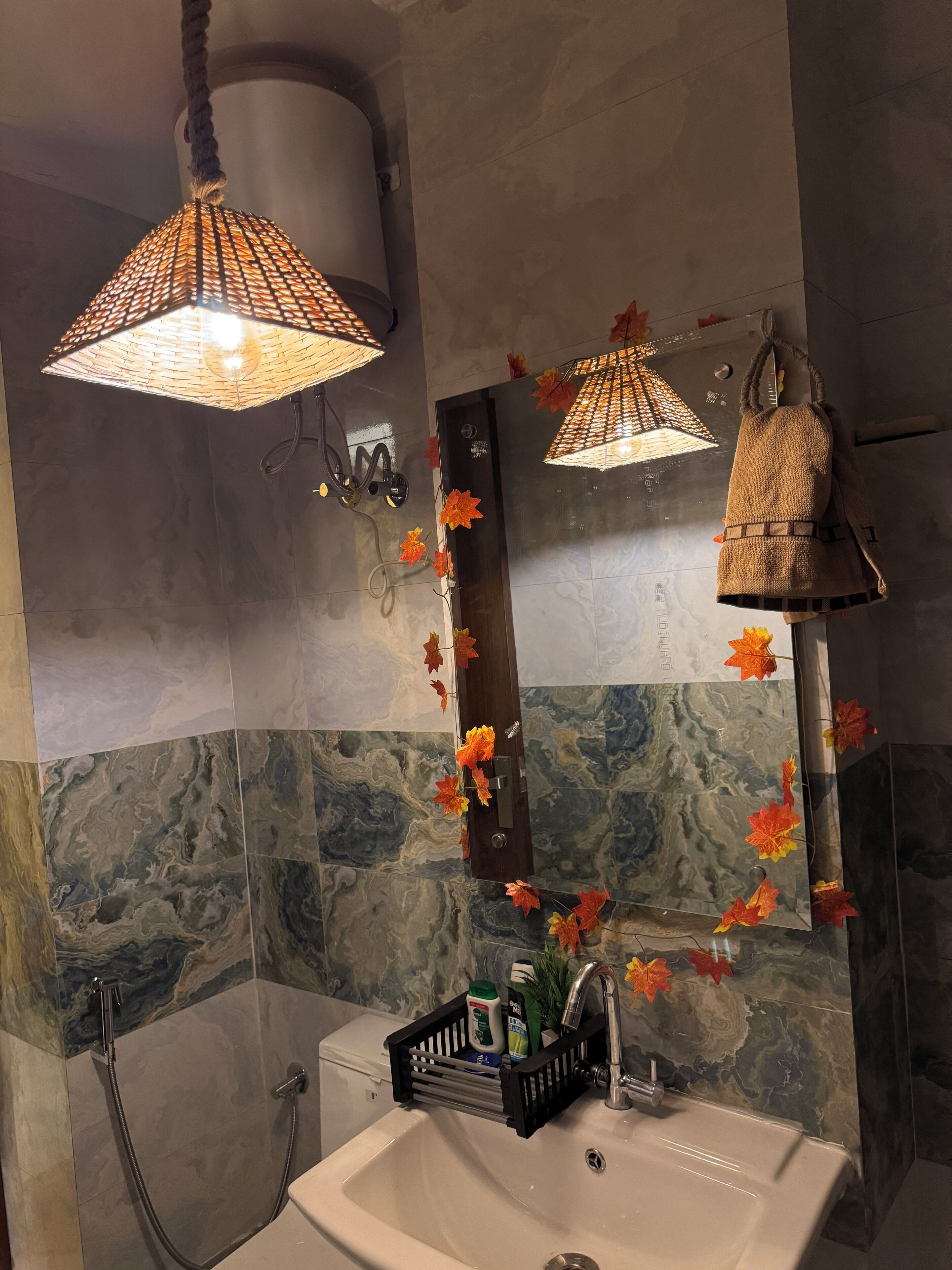 Un baño con pared de mármol, un lavamanos blanco, un espejo y un bolso colgado.