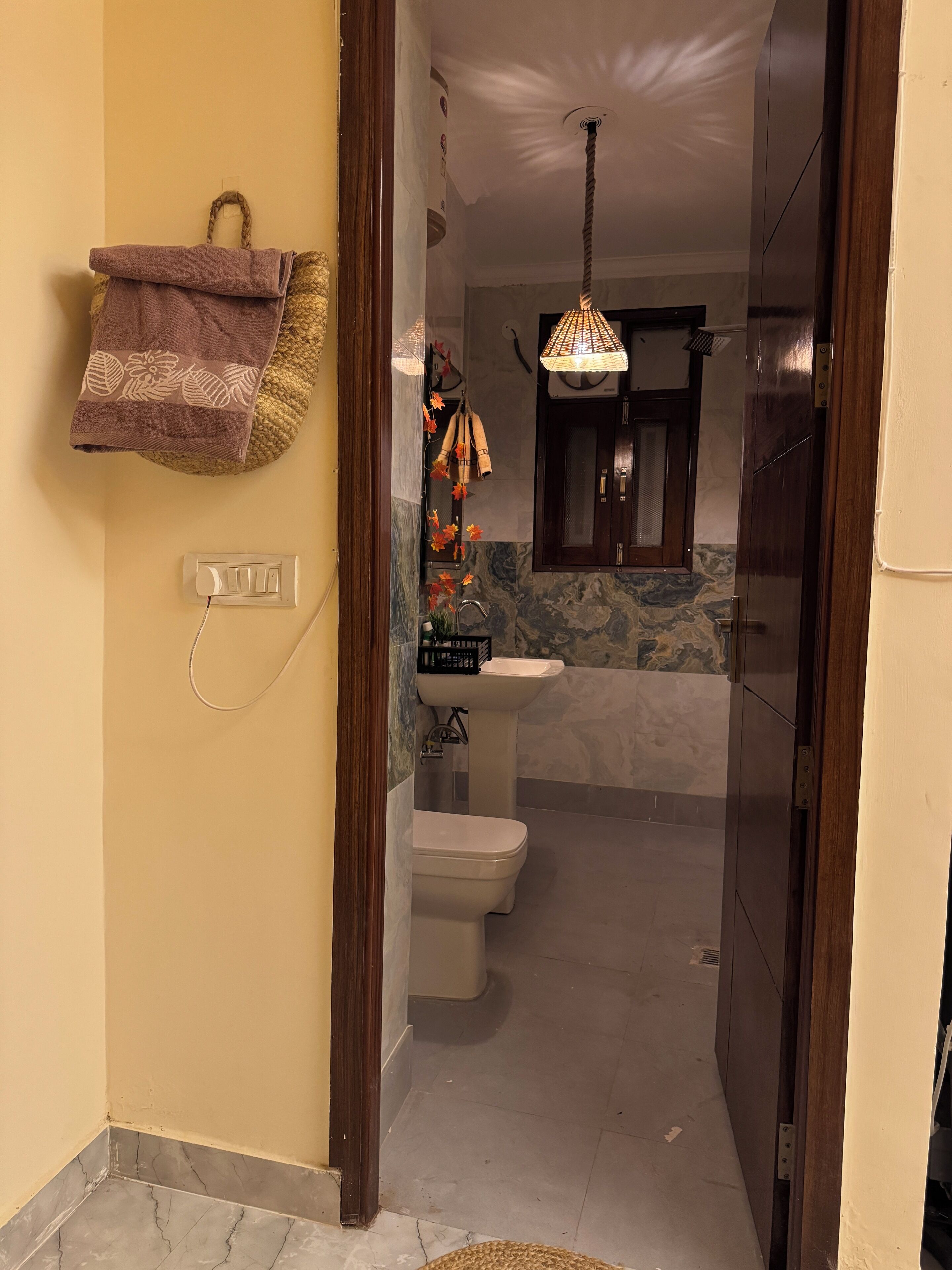 Une salle de bain équipée de toilettes, d’un lavabo et d’éléments décoratifs, comme une serviette et des objets décoratifs suspendus.
