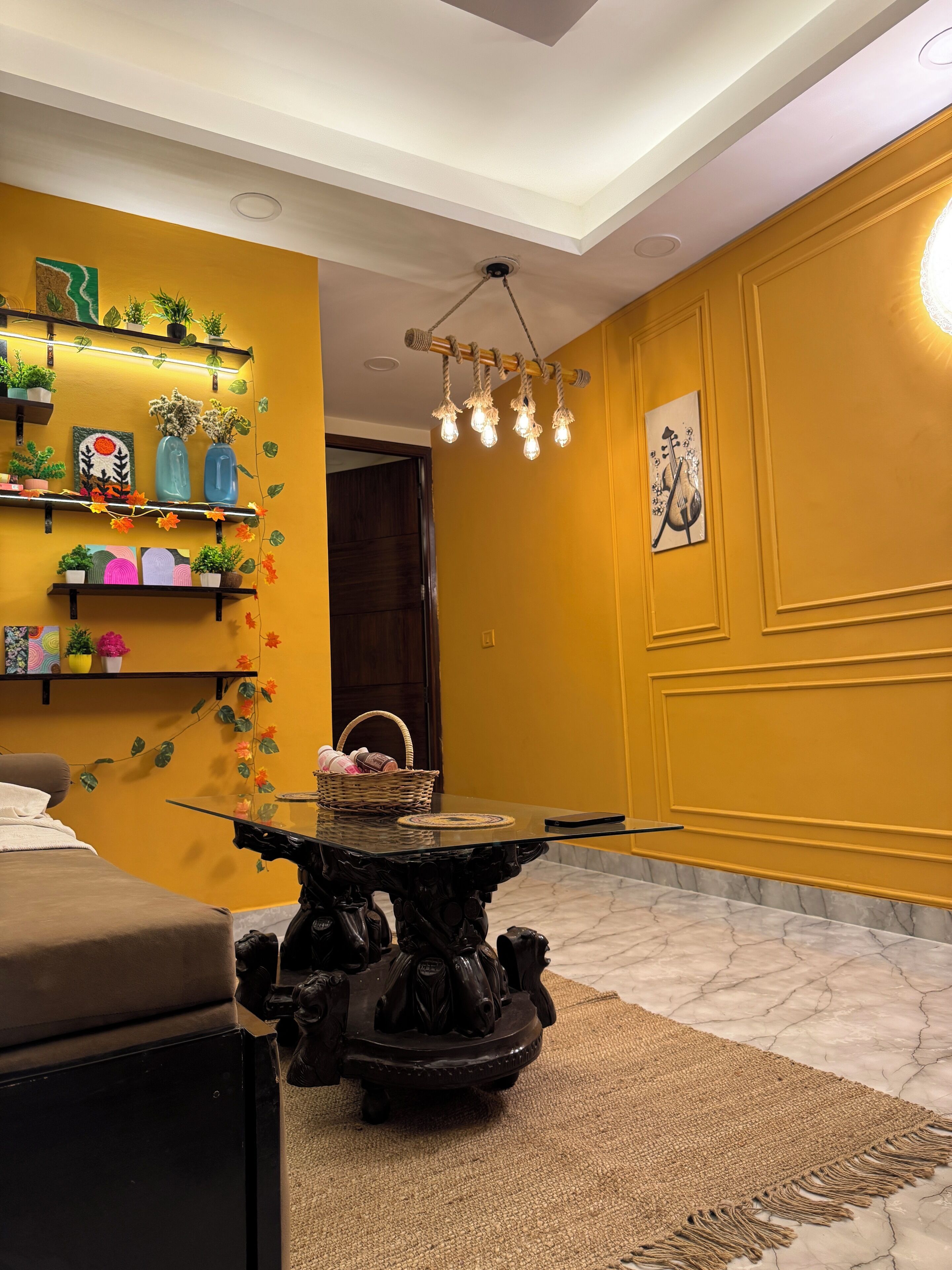 Una habitación con pared amarilla, mesa de madera oscura y lámpara en el techo.