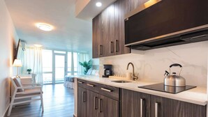 Una cocina moderna con armarios de madera oscura, un hervidor de acero inoxidable y una estufa empotrada.