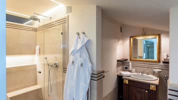 Une salle de bain moderne avec une douche à parois de verre, un meuble-lavabo avec un évier et un miroir, et un peignoir accroché au mur.