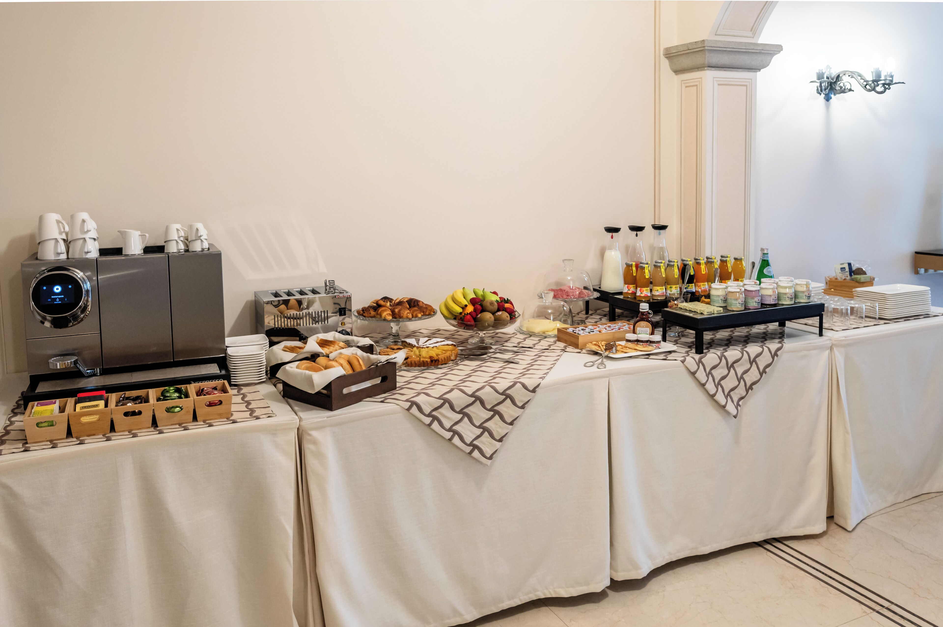 A buffet table with various food items, a coffee machine, and a beverage dispenser.