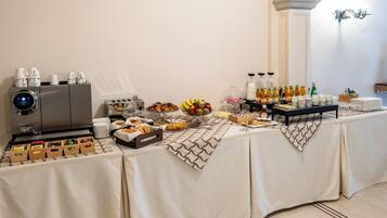 A buffet table with various food items, a coffee machine, and a beverage dispenser.