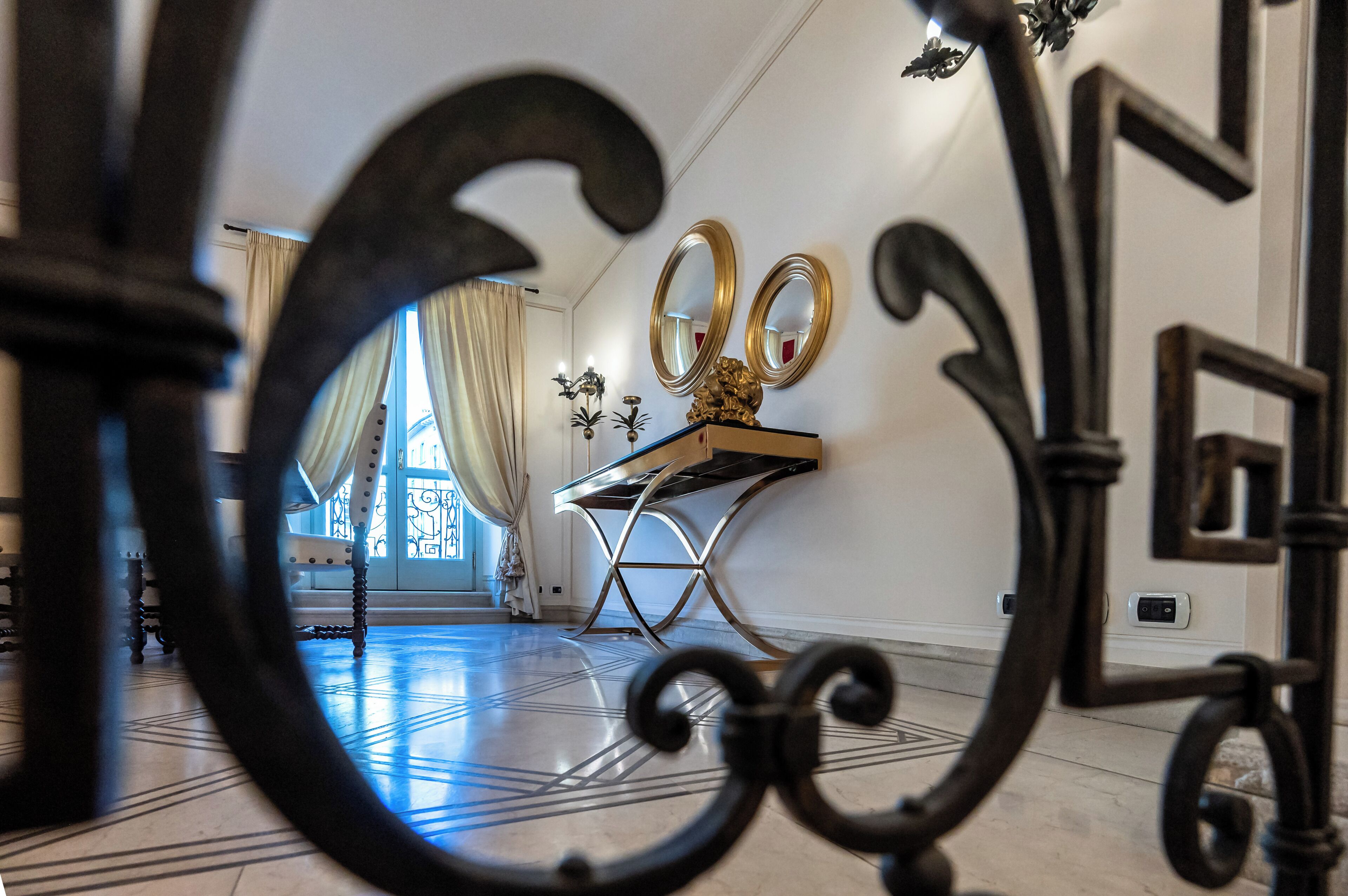 Una habitación con un espejo grande, una mesa con cubierta decorativa y un suelo estampado.