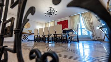 Una stanza con un lampadario, un pianoforte e un'ampia finestra con tende.