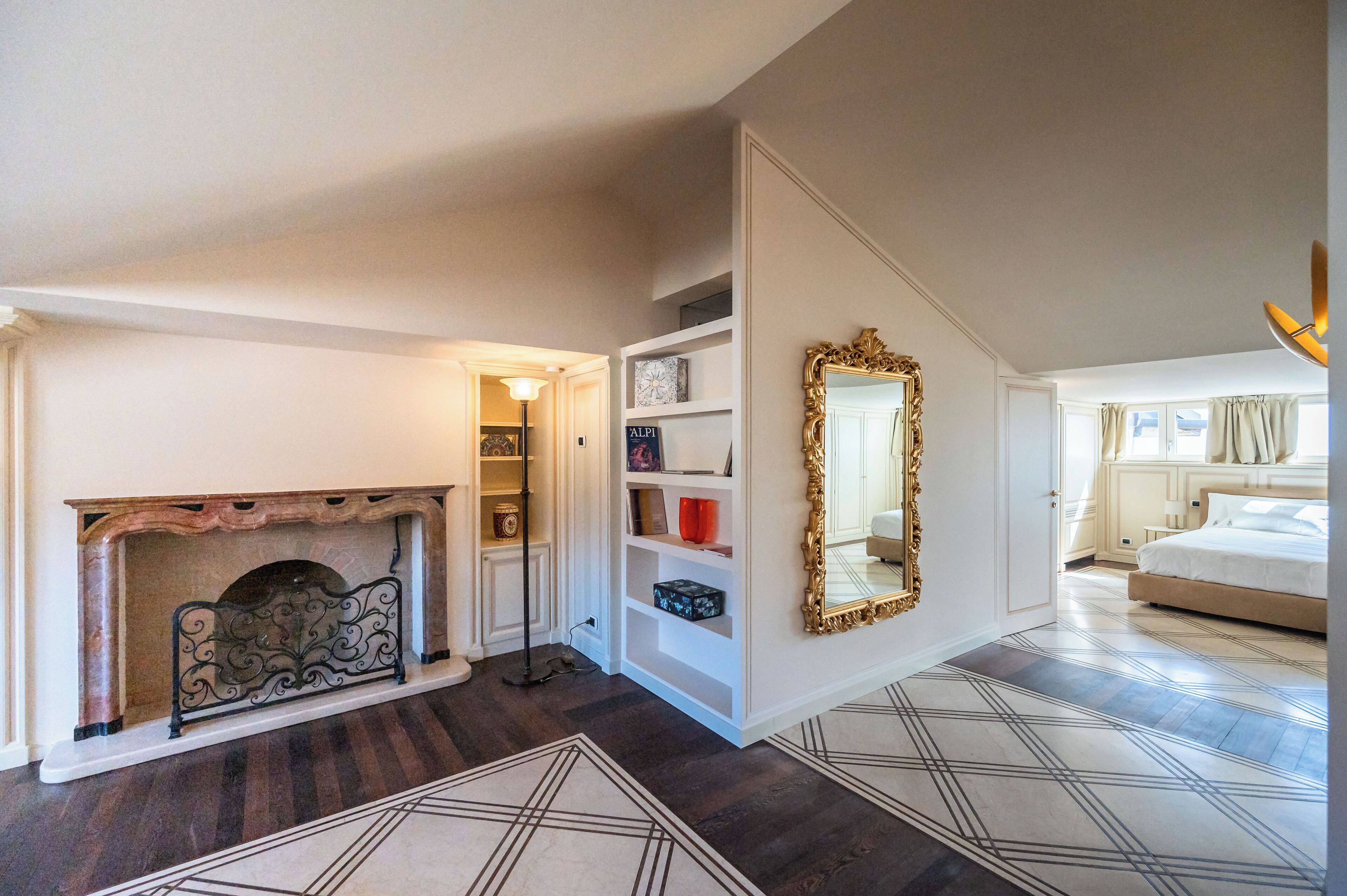 A bedroom with a fireplace, a large mirror, and a bed.