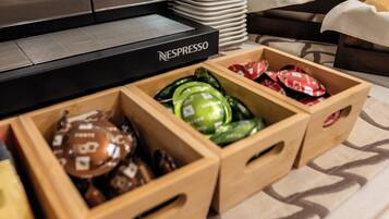 A coffee station with a Nespresso machine and various coffee pods in wooden boxes.