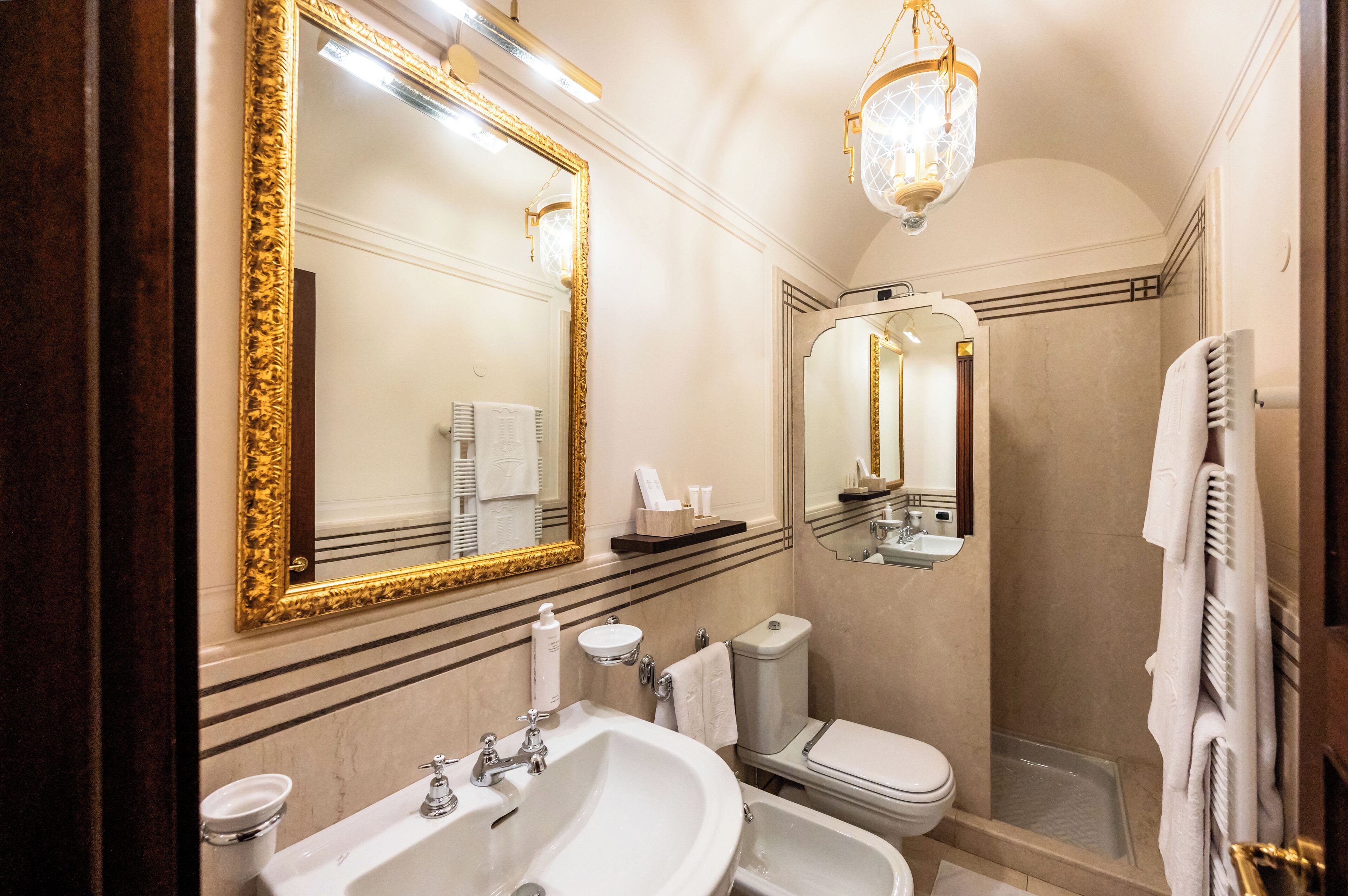 Une salle de bain avec un grand miroir, un lavabo, des toilettes et une douche.
