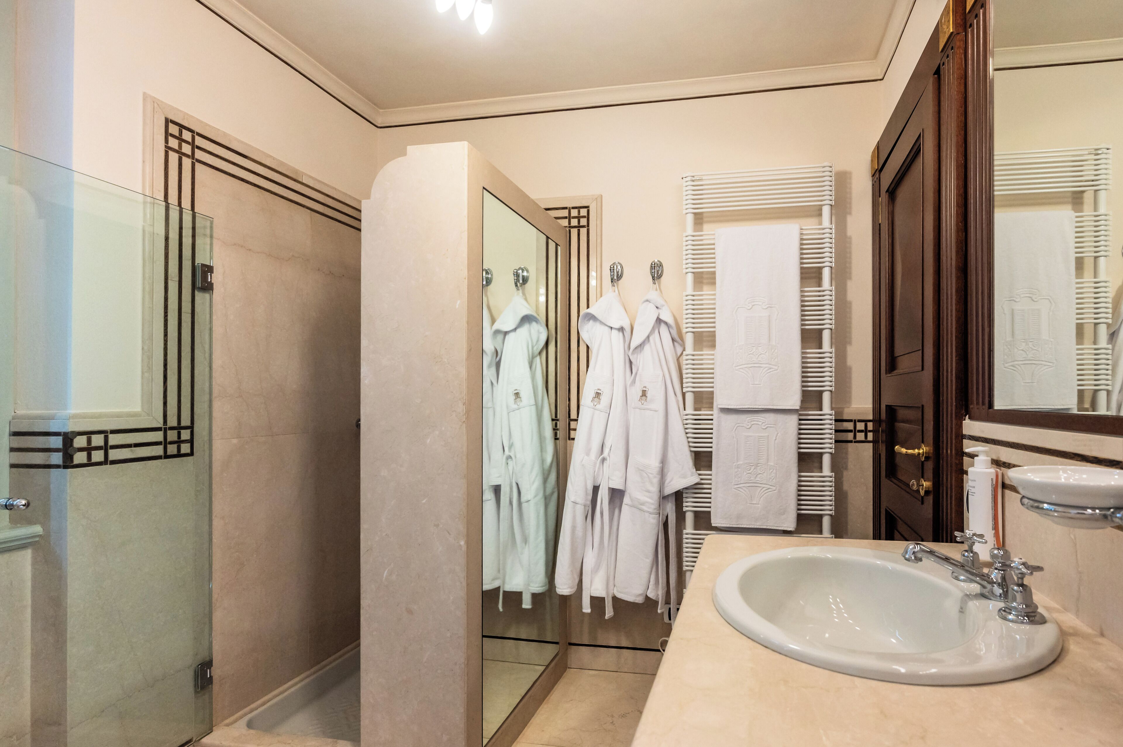 A modern bathroom with a glass shower enclosure, a large mirror, and a sink with a vanity.