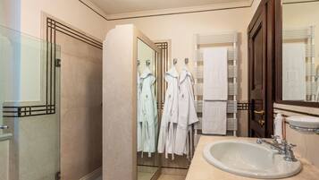 A modern bathroom with a glass shower enclosure, a large mirror, and a sink with a vanity.