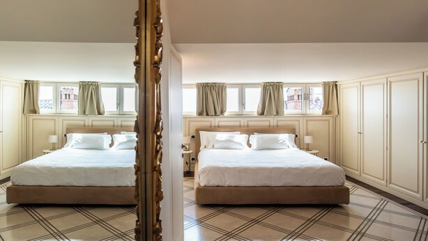 Una cama doble con cabecera, una mesita de noche con lámpara y una ventana con cortinas.