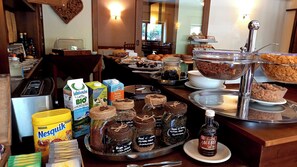 A breakfast buffet with various food items, including jars of spreads, a bottle of syrup, and cartons of milk. - Hotel Comelico (Padola)