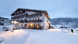 A hotel with a multi-story structure, a bar, and a sign indicating it is a hotel. - Hotel Comelico (Padola)