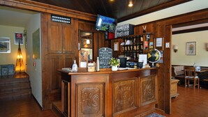 A wooden reception desk with a television, a globe, and a menu board. - Hotel Comelico (Padola)