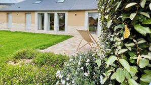A modern house with a large glass door, a well-maintained lawn, and a garden area.