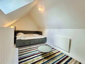 Un dormitorio con cama, mesita de noche y un radiador.
