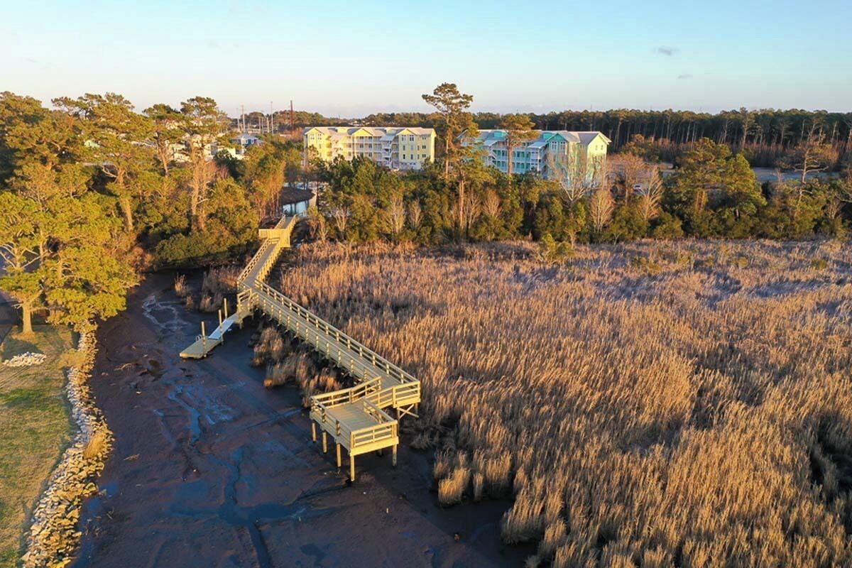 A bridge leading to a building complex surrounded by dense vegetation.