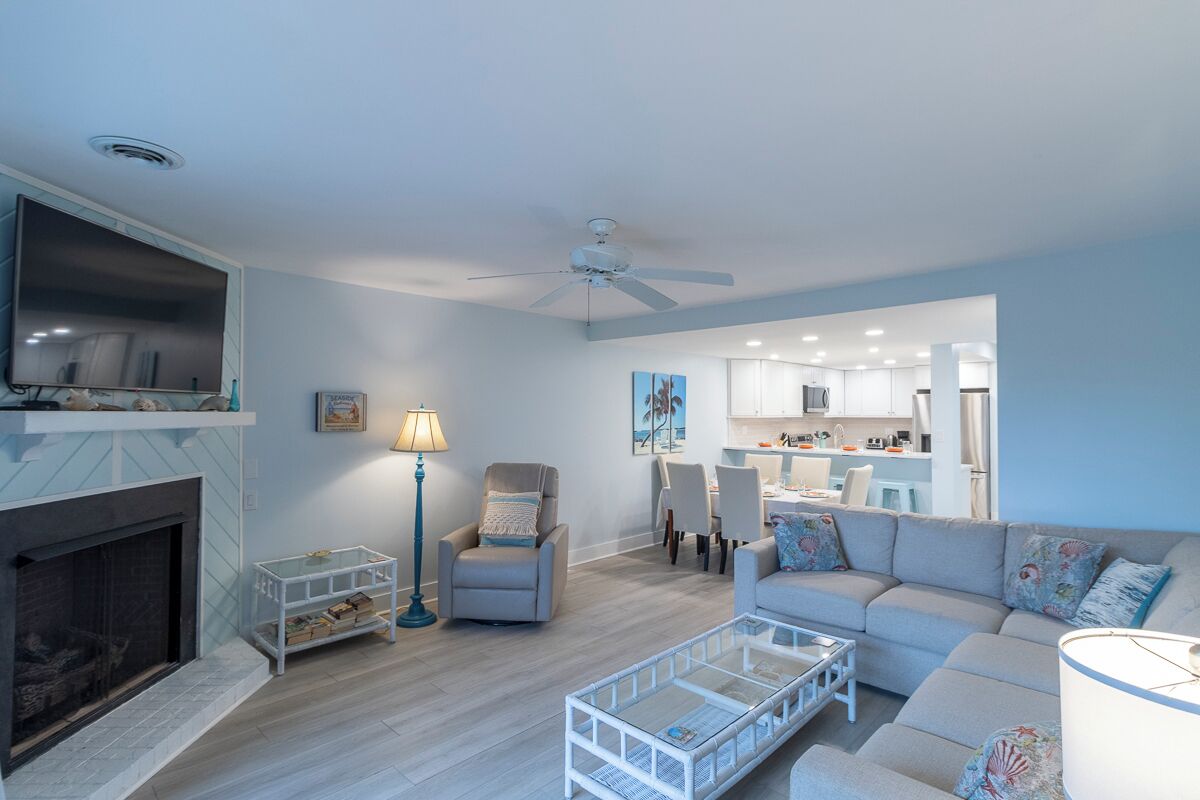 Ein modernes Wohnzimmer mit Kamin, Deckenventilator und einer Couch.
