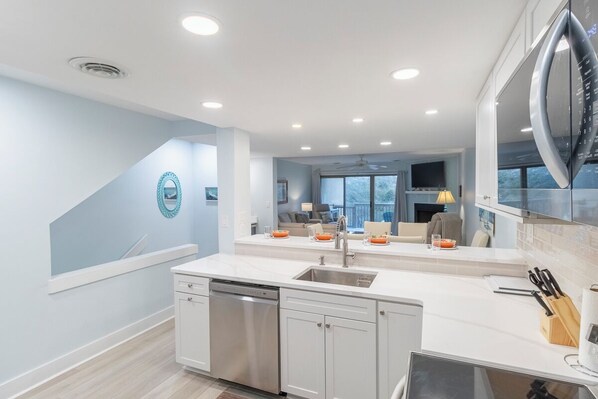 A modern kitchen with a dishwasher, sink, and stainless steel appliances. - Newly updated oceanfront condo in Nags Head! (Nags Head)