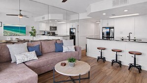 Una sala de estar moderna con sofá, mesa de centro y taburetes de bar.