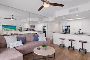 A modern living room with a sofa, coffee table, and bar stools. - Gulfview I 314 – Stunning Gulf Views, Gated Beach Across Street, Walk to Dining (Destin)