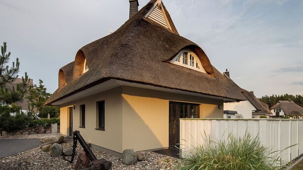 A thatched-roof house with a small porch and a stone pathway leading to the entrance. - Thatched roof vacation home Ankerplatz in Fuhlendorf am Bodden (Fuhlendorf)