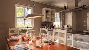 A dining area with a wooden table set for a meal, surrounded by white chairs. - Thatched roof vacation home Ankerplatz in Fuhlendorf am Bodden (Fuhlendorf)