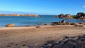A rocky beach with clear blue water, large boulders, and a distant island. - "La Pagode"close to beache (Trégastel)