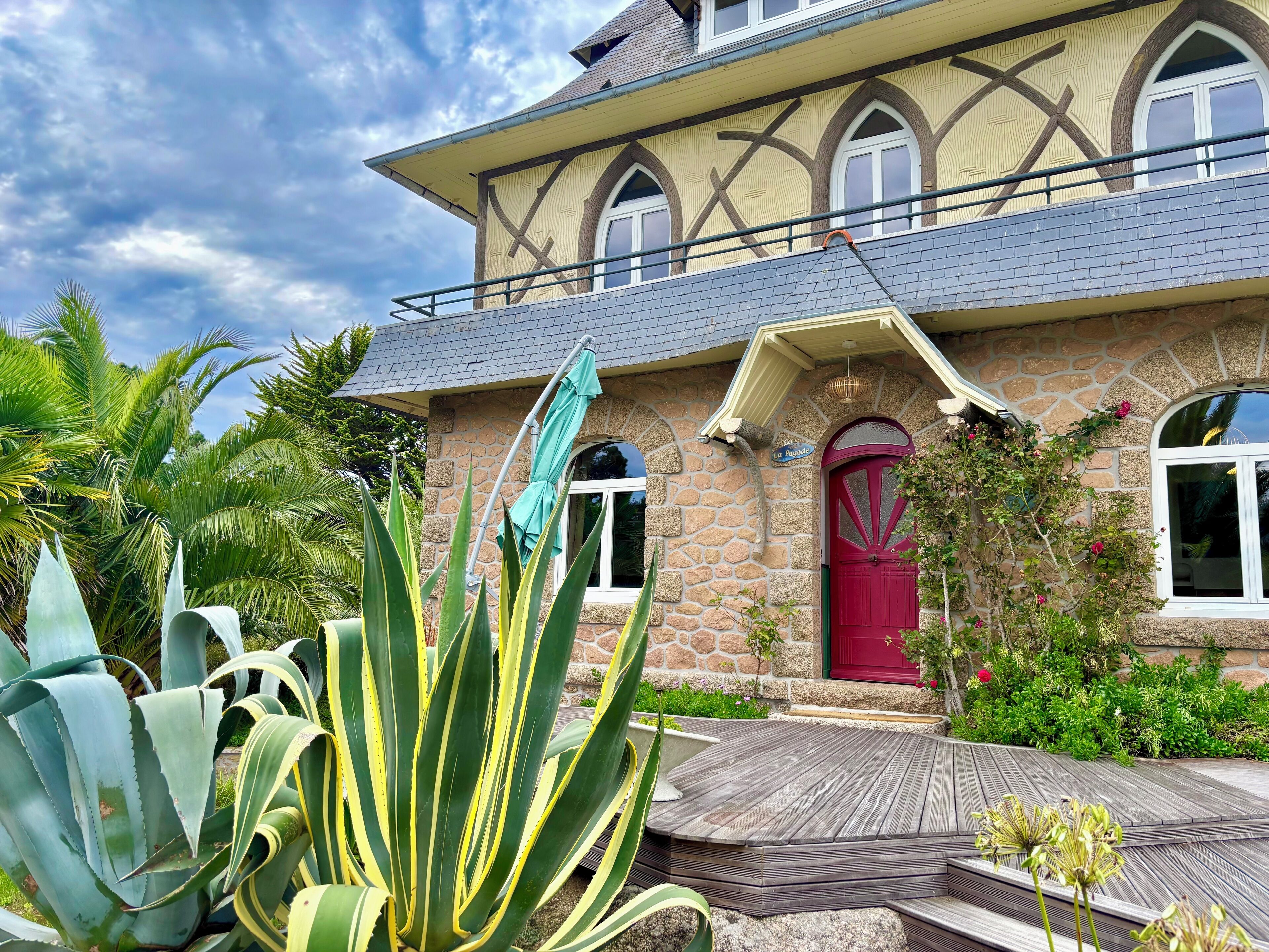 A stone house with a red door, a balcony, and a sign reading "La Parade."