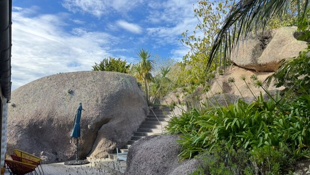 A staircase leading up a rocky slope with outdoor seating and a view of the sky. - "La Pagode"close to beache (Trégastel)