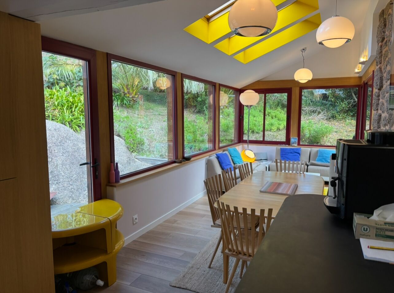 A modern kitchen with a large island, wooden chairs, and a dining table.