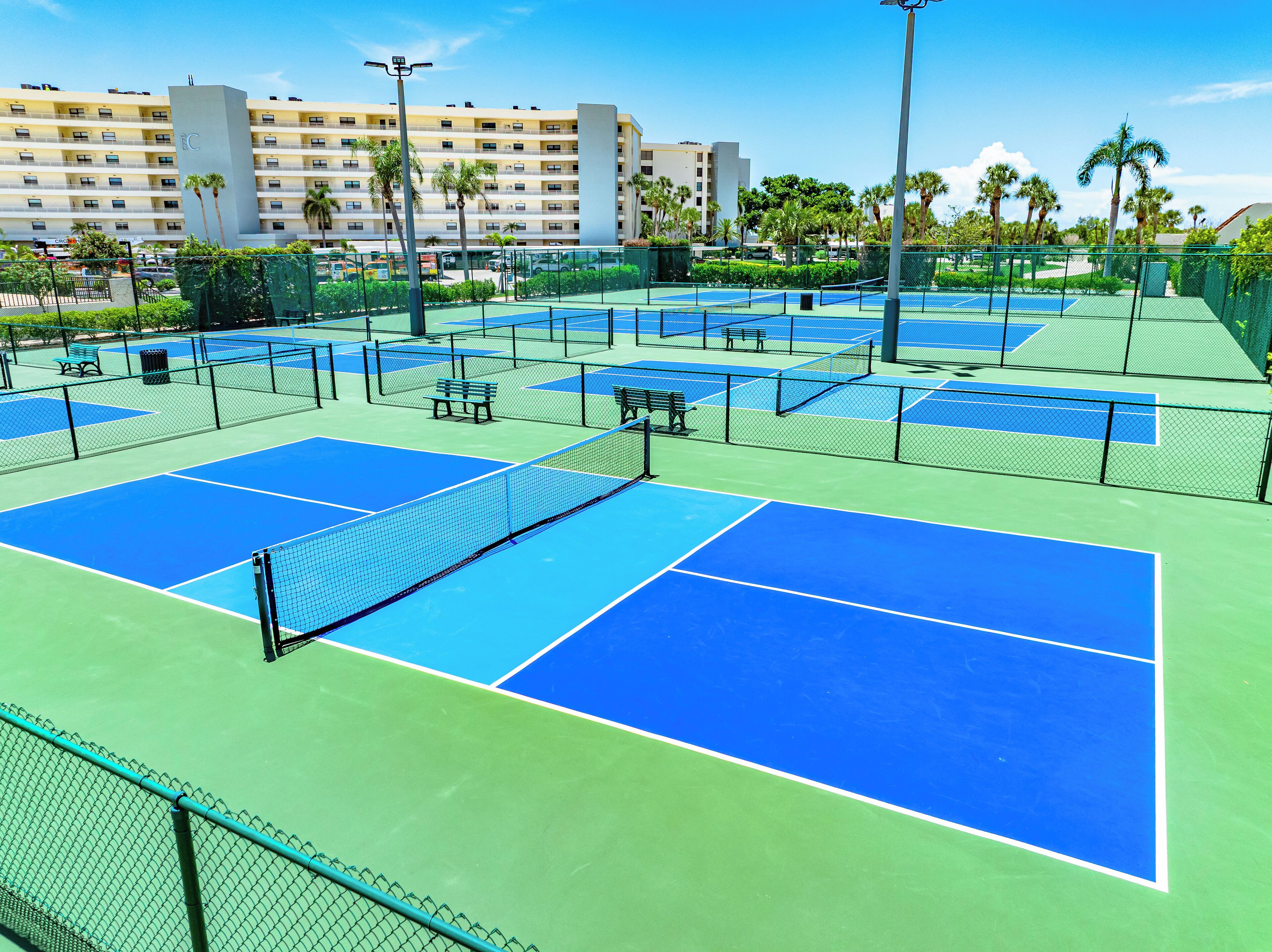 Camp de tennis amb pistes múltiples, bancs i una tanca.