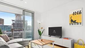 A modern living room with a sofa, a coffee table, a TV, and a city view.