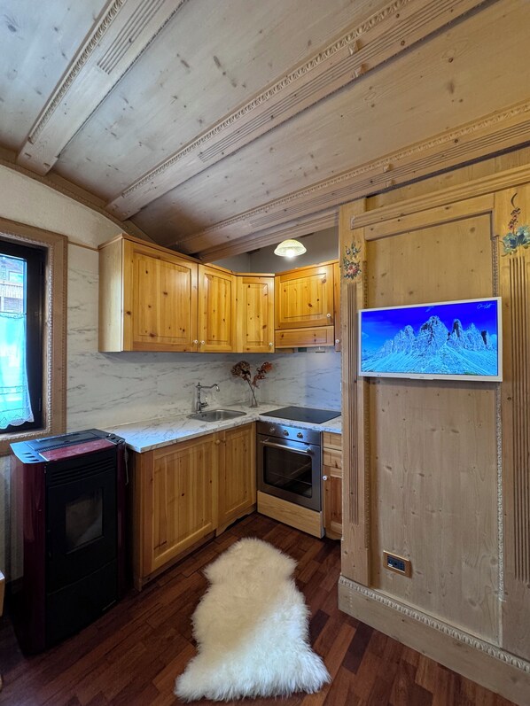 A kitchen with wooden cabinets, a marble countertop, a stove, and a white fur rug.