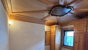 Quarto com cama, teto de madeira e janela com cortinas.