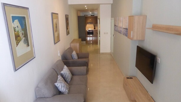 A modern living room with a sofa set, a flat-screen TV, and framed artwork on the walls. - Seaview Ground Floor Flat Wheelchair Friendly (Zebbug)