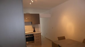 A compact kitchen with modern appliances, a dining table with chairs, and a visible oven. - Seaview Ground Floor Flat Wheelchair Friendly (Zebbug)